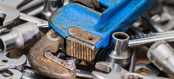 plumber's blue wrench sitting on top of other tools as he diagnoses an issue 