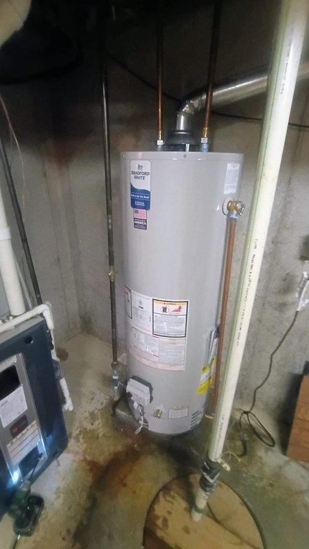 Installed 40-gallon tanked water heater in basement utility area per specifications. Connected copper supply lines and plumbing connections at top of unit, verified all pipe fittings secure and leak-free. Unit positioned on concrete floor with proper clearances, all manufacturer labels and energy guide information visible and intact for future reference.