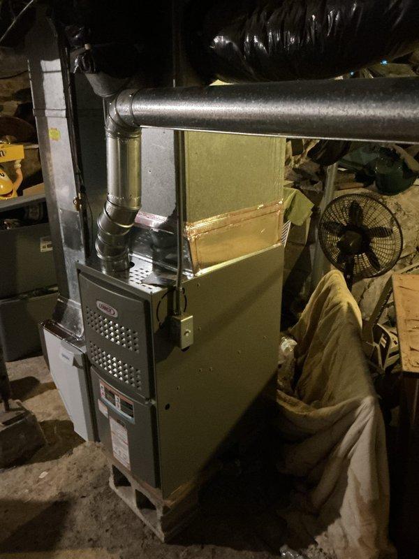 Successfully installed a Lennox ML180UH070 furnace with T4 thermostat in basement utility area. Connected unit to existing return air system and verified integrity of existing ventilation piping with no compromises detected. System is properly mounted on concrete floor with all ductwork securely attached and operational.