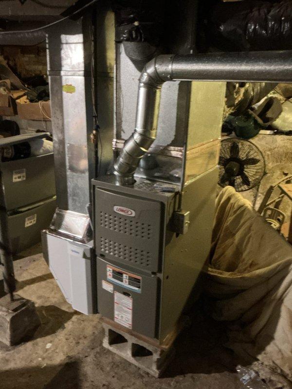 Successfully installed a Lennox ML180UH070 furnace with T4 thermostat in basement utility area. Connected unit to existing return air system and verified integrity of existing ventilation piping with no compromises detected. System is properly mounted on concrete floor with all ductwork securely attached and operational.