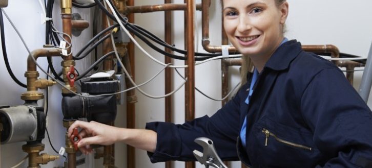 Female plumber working on central heating boiler
