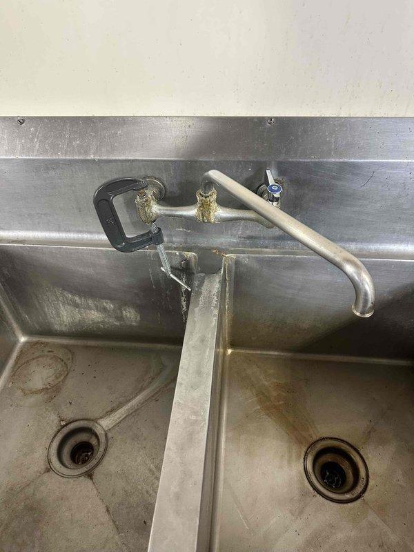 Successfully replaced faucet at commercial wash station featuring a double basin stainless steel sink. Installed new gooseneck-style faucet with dual hot/cold handles, ensuring proper connection to existing plumbing system.