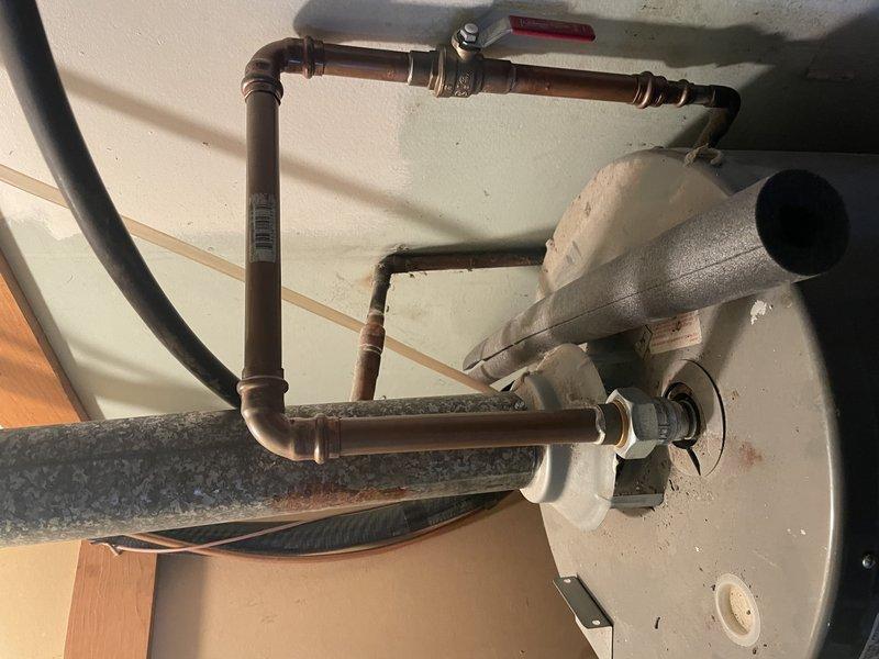 Responded to service call for non-functioning tanked water heater, approximately 5-6 years old. Diagnosed ignition failure and repaired minor water leak observed at copper pipe connections. Inspected aging copper piping showing oxidation and patina development, particularly at joints and 90-degree bends, and verified proper function of pressure relief valve system.