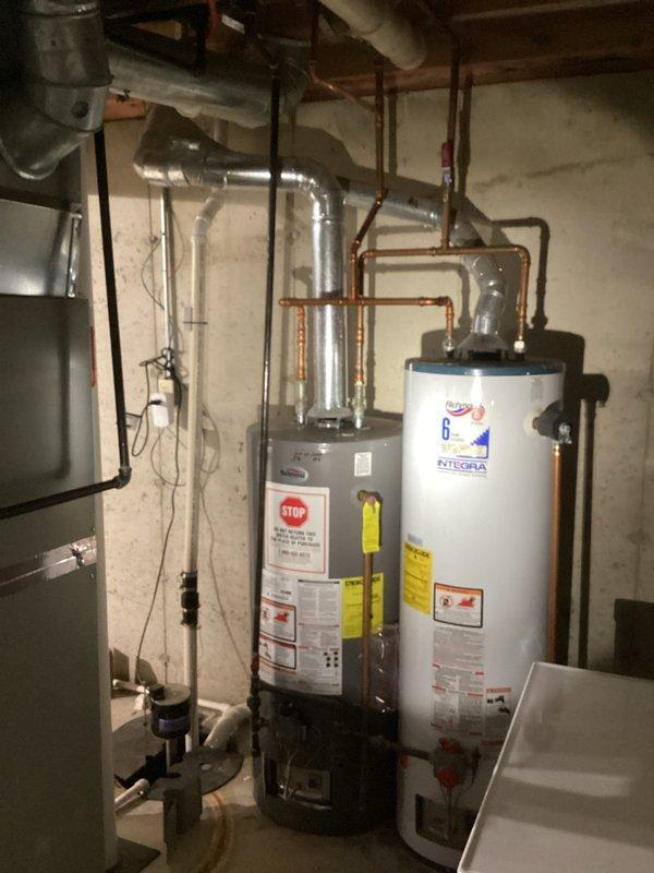 Responded to no hot water complaint at residence with two water heater system (standard unit and Integra model). Inspection revealed significant corrosion and rust on vertical pipe connections with failing rubber couplings. Replaced deteriorated components and restored hot water service to the property.