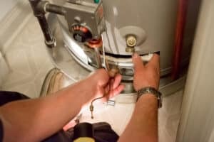 Man shines flashlight on water heater