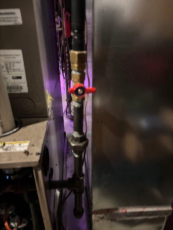 Niles, MI - Inspected plumbing assembly with black pipe and brass fittings. Identified functional red valve handle for system isolation. Verified proper connection to HVAC/water system with operational indicator lighting.
