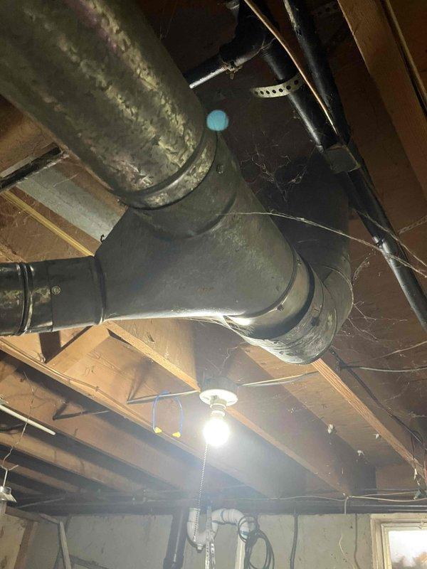 Conducted comprehensive evaluation of existing HVAC system in unfinished basement area. Inspected large galvanized metal ductwork with Y-shaped junction connections, noting age-related dust accumulation and potential airflow inefficiencies. Examined furnace unit, temperature control system, and associated PVC venting for replacement assessment. Documented current system condition with photos to develop appropriate replacement specifications.