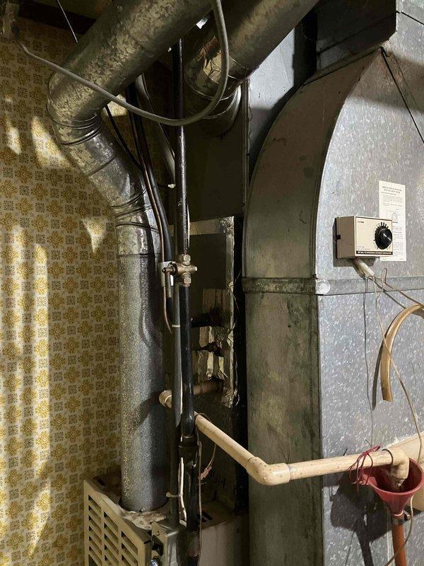 Conducted comprehensive evaluation of existing HVAC system in unfinished basement area. Inspected large galvanized metal ductwork with Y-shaped junction connections, noting age-related dust accumulation and potential airflow inefficiencies. Examined furnace unit, temperature control system, and associated PVC venting for replacement assessment. Documented current system condition with photos to develop appropriate replacement specifications.