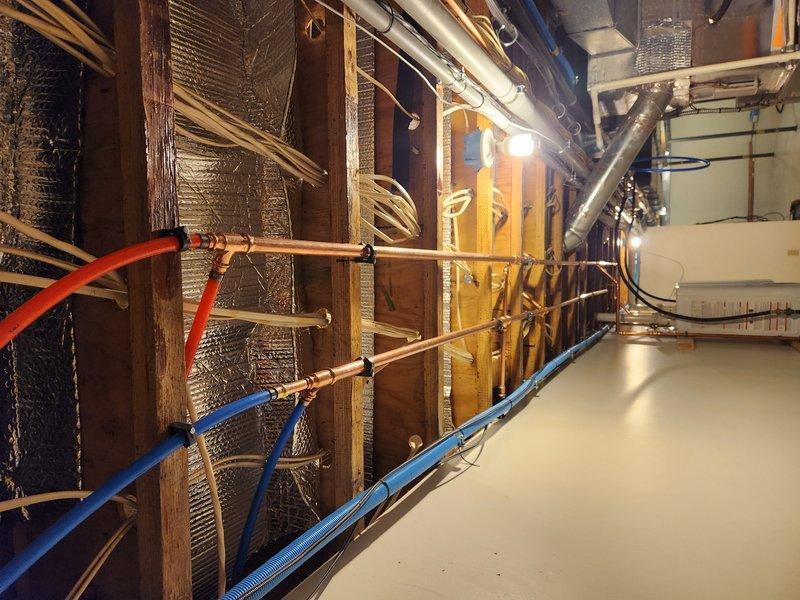 Completed installation of dual Navien NPE240A2 tankless water heaters, relocating one existing unit and adding a second unit to support bathroom remodel. Installed new copper supply lines with press fittings and connected PEX distribution lines for hot and cold water service. Mounted units on wooden support frames with proper venting and electrical connections.