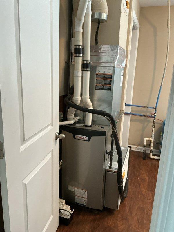 Completed installation of Lennox EL297UH070 furnace, successfully connecting unit to existing thermostat and return air filter system. Post-installation temperature testing confirmed proper system operation with readings at 14.8°F at the register. Installation includes properly configured PVC ventilation pipes with secure connection points.