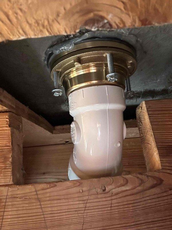 Completed master shower drain removal and replacement due to deteriorated fixture. Removed existing drain assembly from master bathroom shower, including flange and connecting piping. Installed new PVC drain pipe with proper brass threaded drain flange, secured with mounting hardware and rubber gasket to ensure watertight seal against subfloor. Verified proper alignment and secure attachment through floor joists, with flexible coupling at lower connection point for system integration.