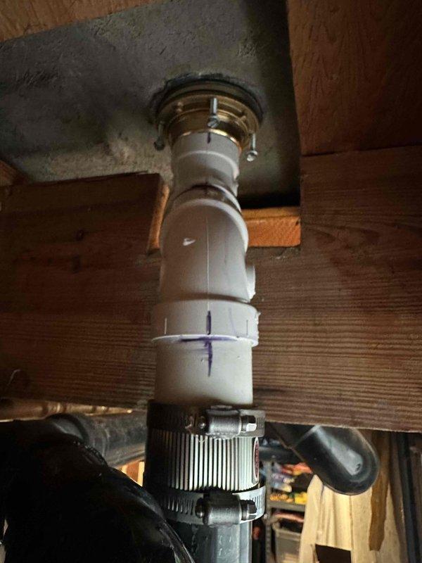 Completed master shower drain removal and replacement due to deteriorated fixture. Removed existing drain assembly from master bathroom shower, including flange and connecting piping. Installed new PVC drain pipe with proper brass threaded drain flange, secured with mounting hardware and rubber gasket to ensure watertight seal against subfloor. Verified proper alignment and secure attachment through floor joists, with flexible coupling at lower connection point for system integration.